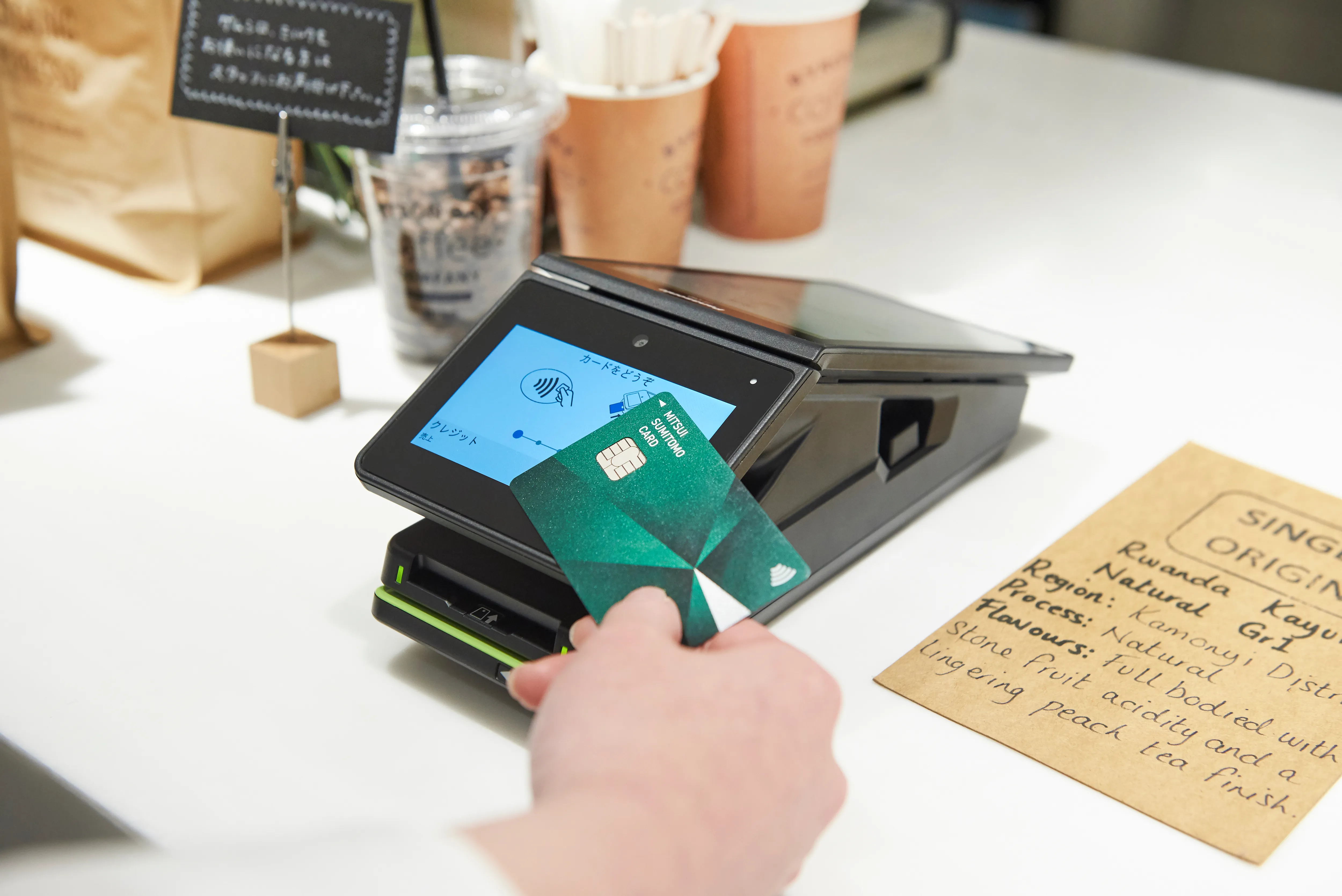 店舗の決済端末でクレジットカードをタッチして支払う様子